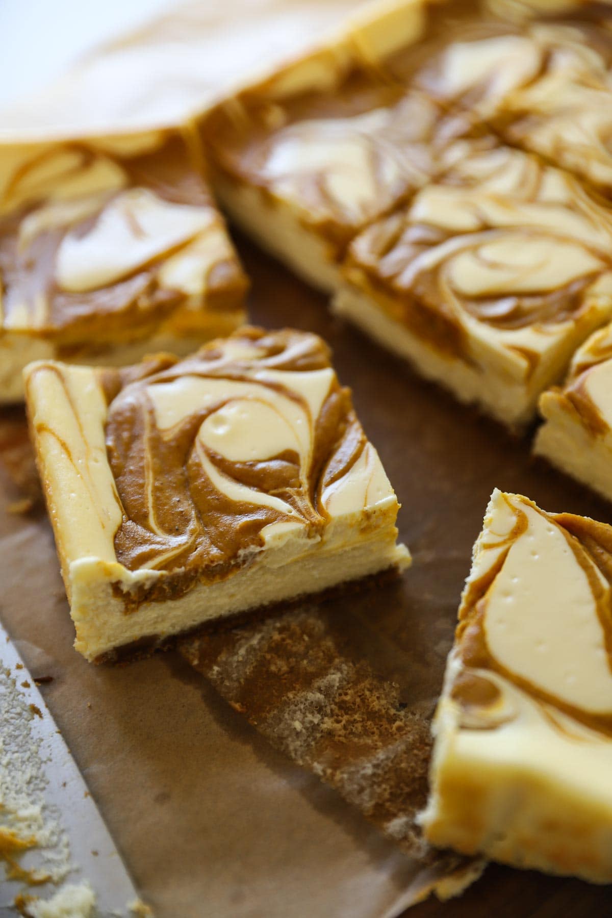 a pumpkin cheesecake bar sliced on parchment paper