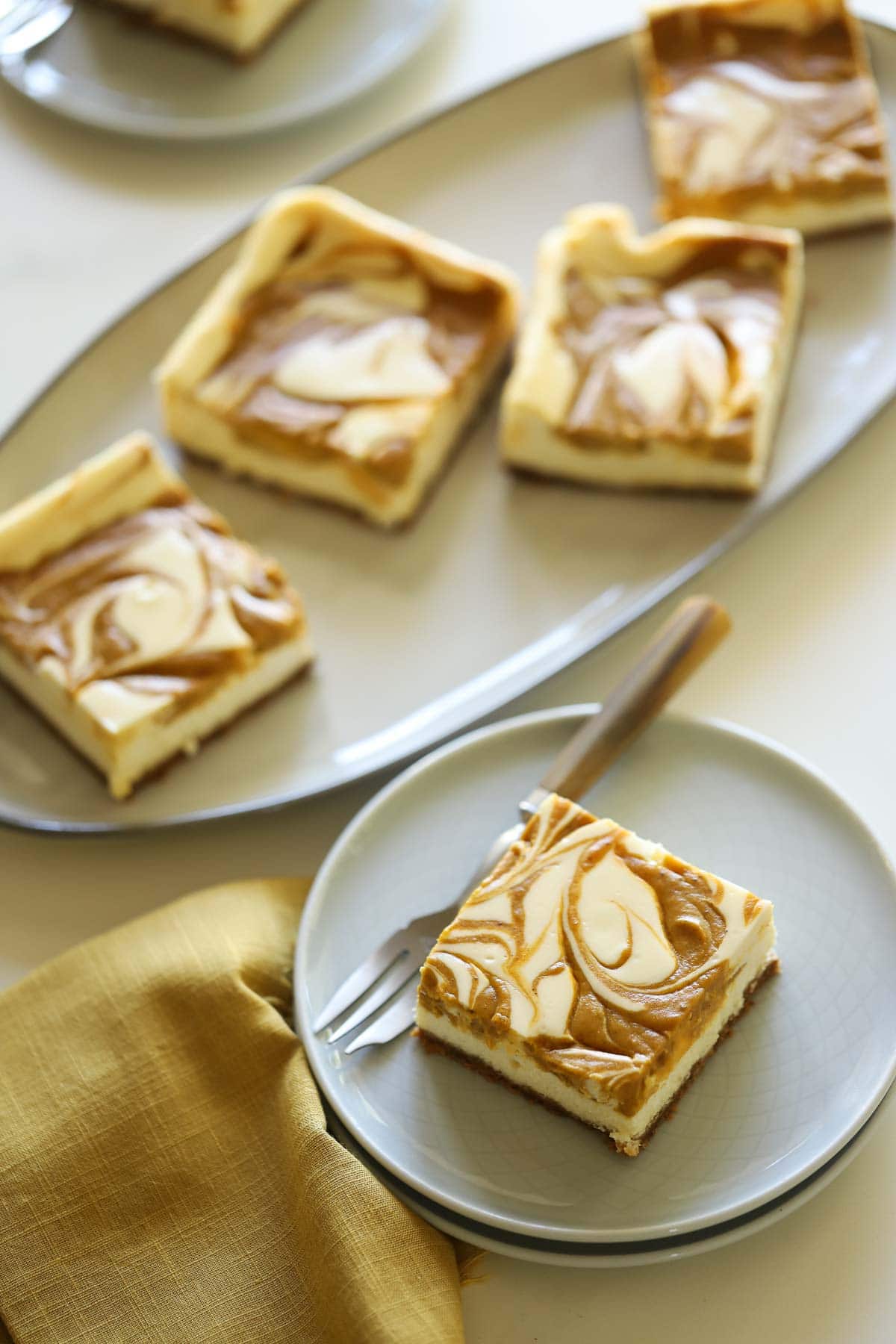 Sliced pumpkin bars on a plate with serving platter in background