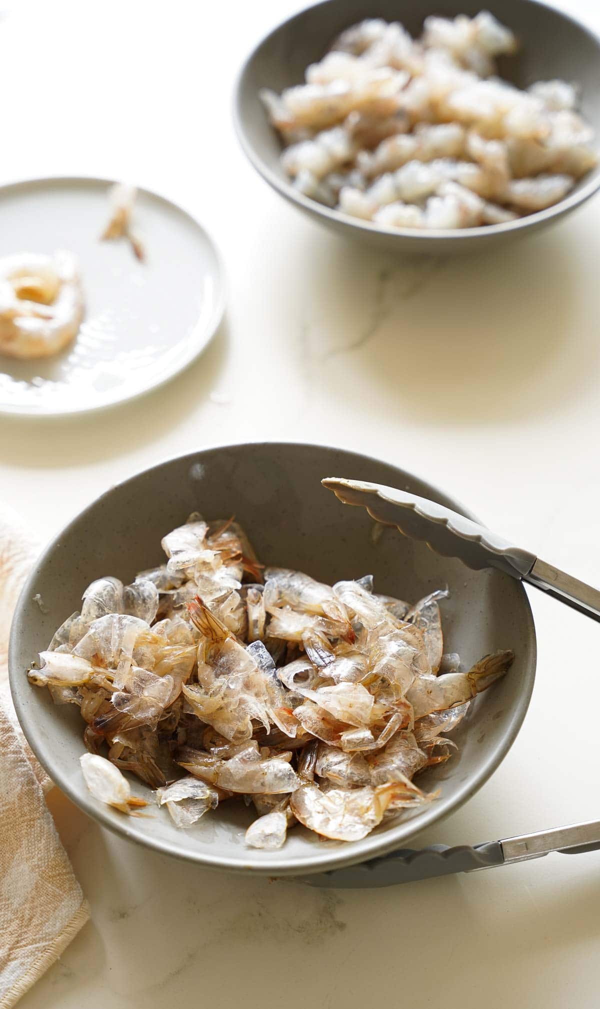 Shrimp shells and shrimp meat separated in bowls on a counter