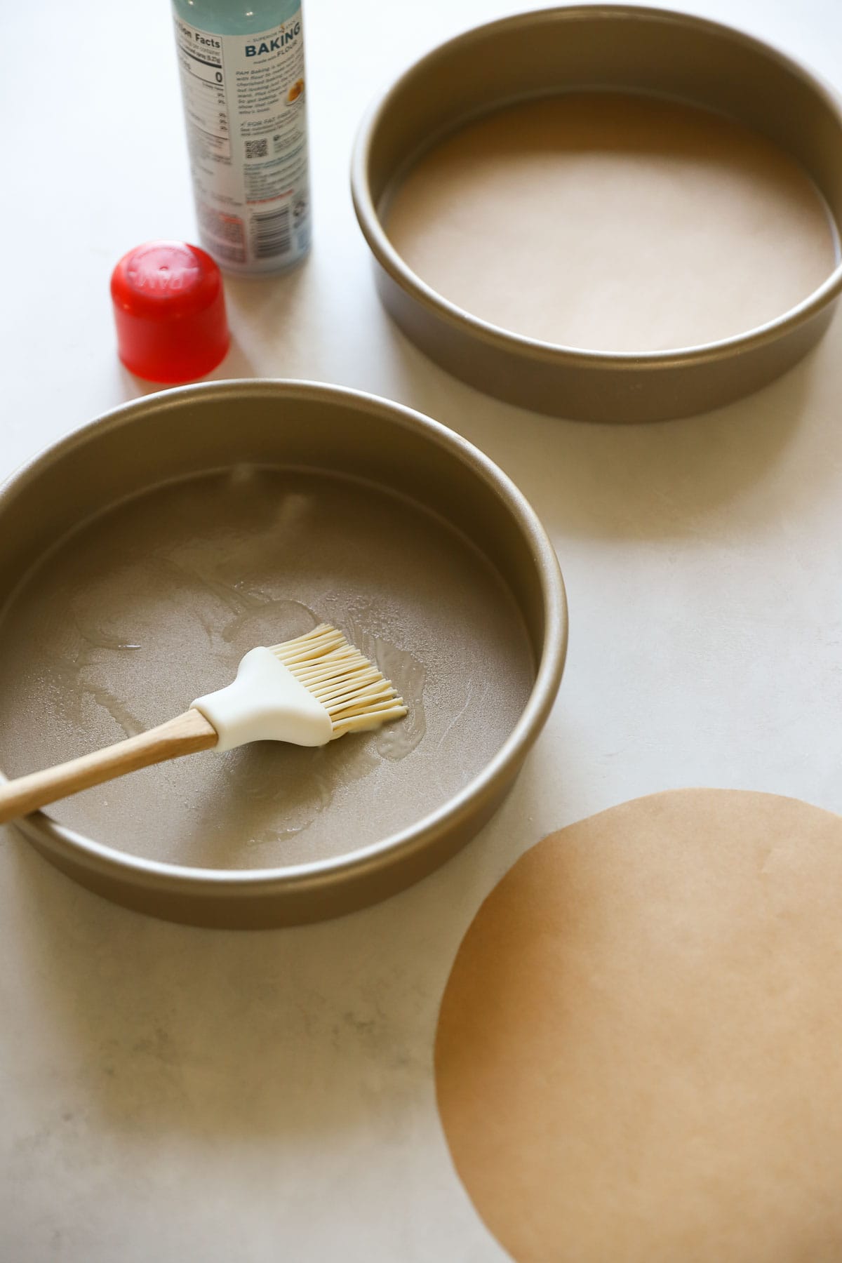 Cake pans getting baking spray and parchment paper