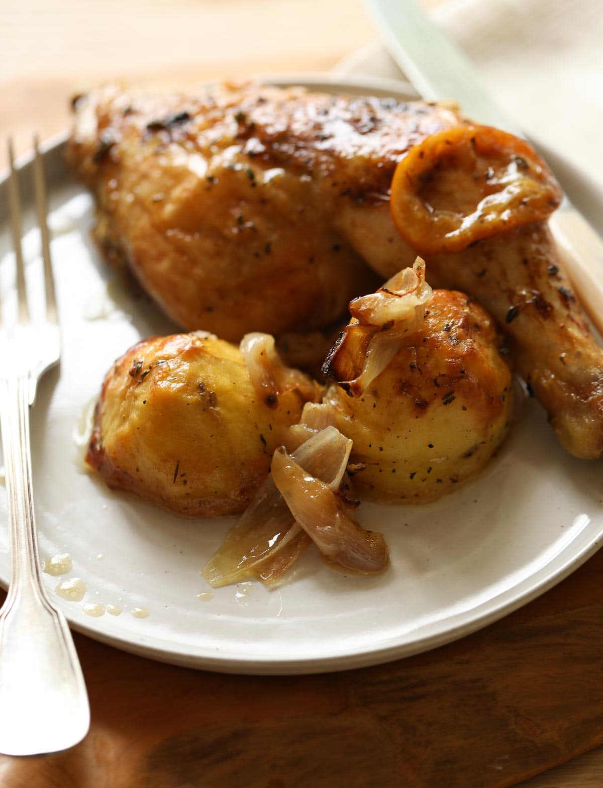 a plate with a single roasted chicken leg and potatoes.