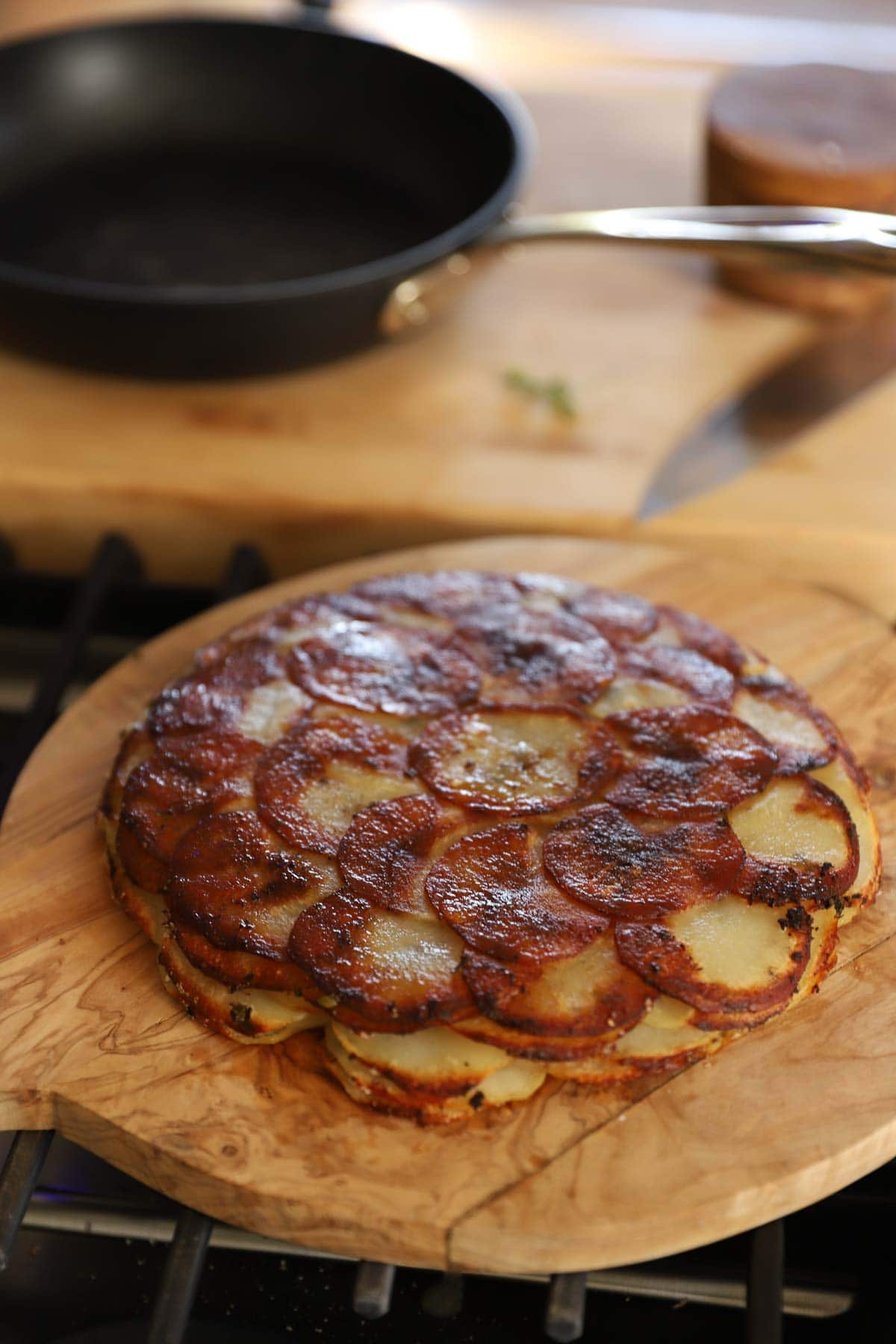 A potato cake crispy on top on a cutting board.