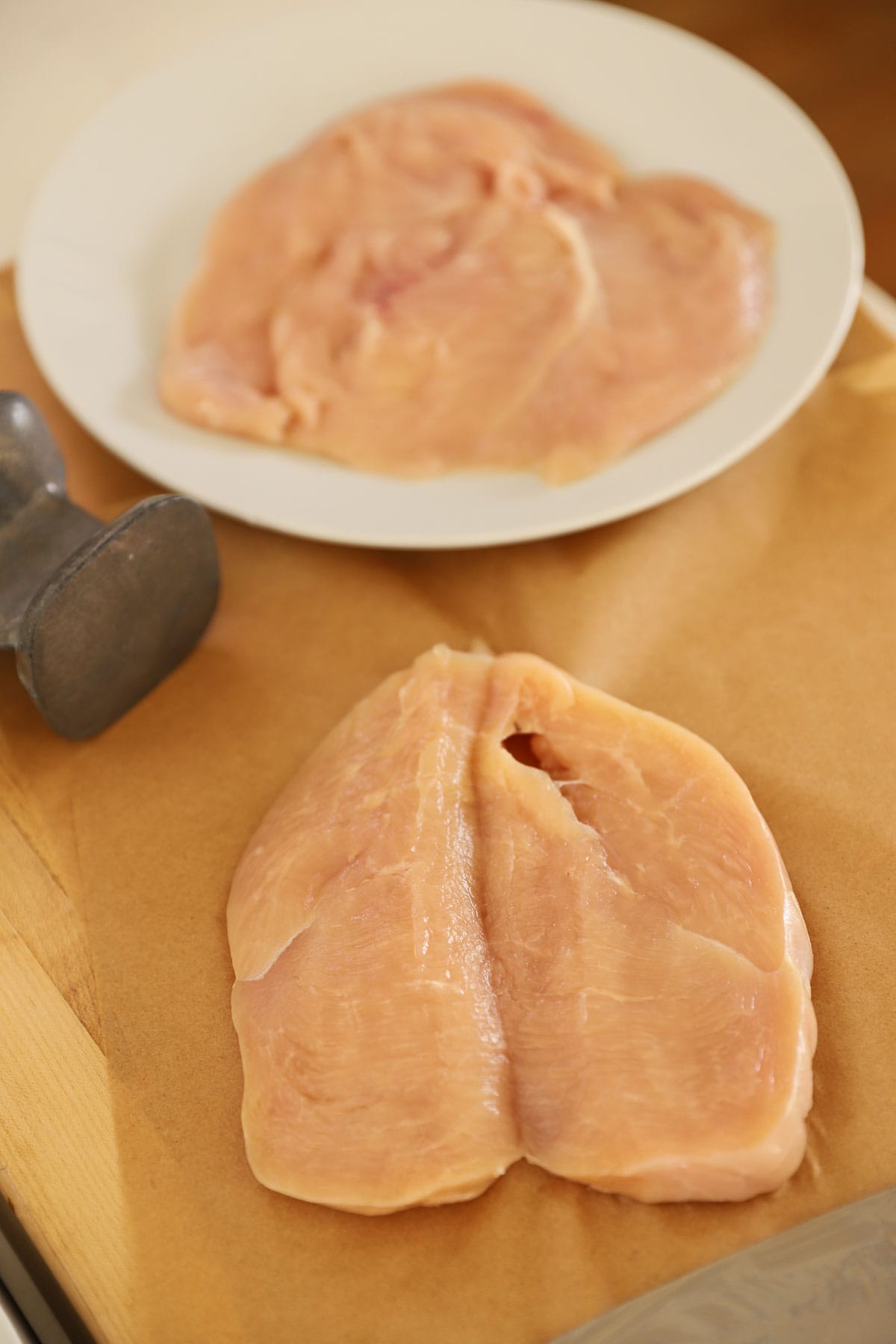 a pounded and butterflied chicken breast on parchment paper.