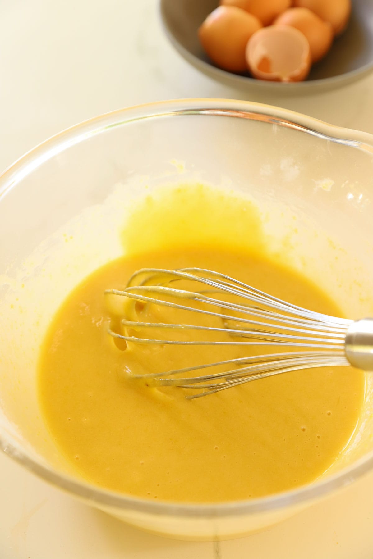 batter in a clear bowl with a whisk.