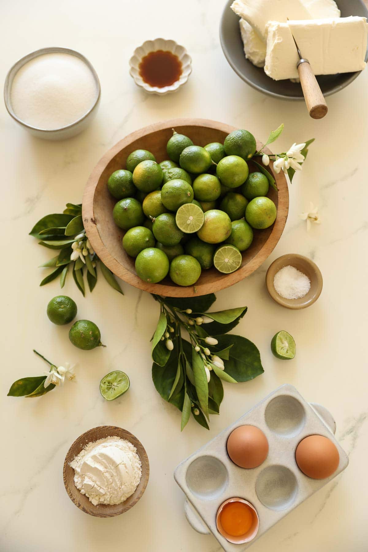 key limes, cream cheese, sugar and other ingredients laid out on counter.