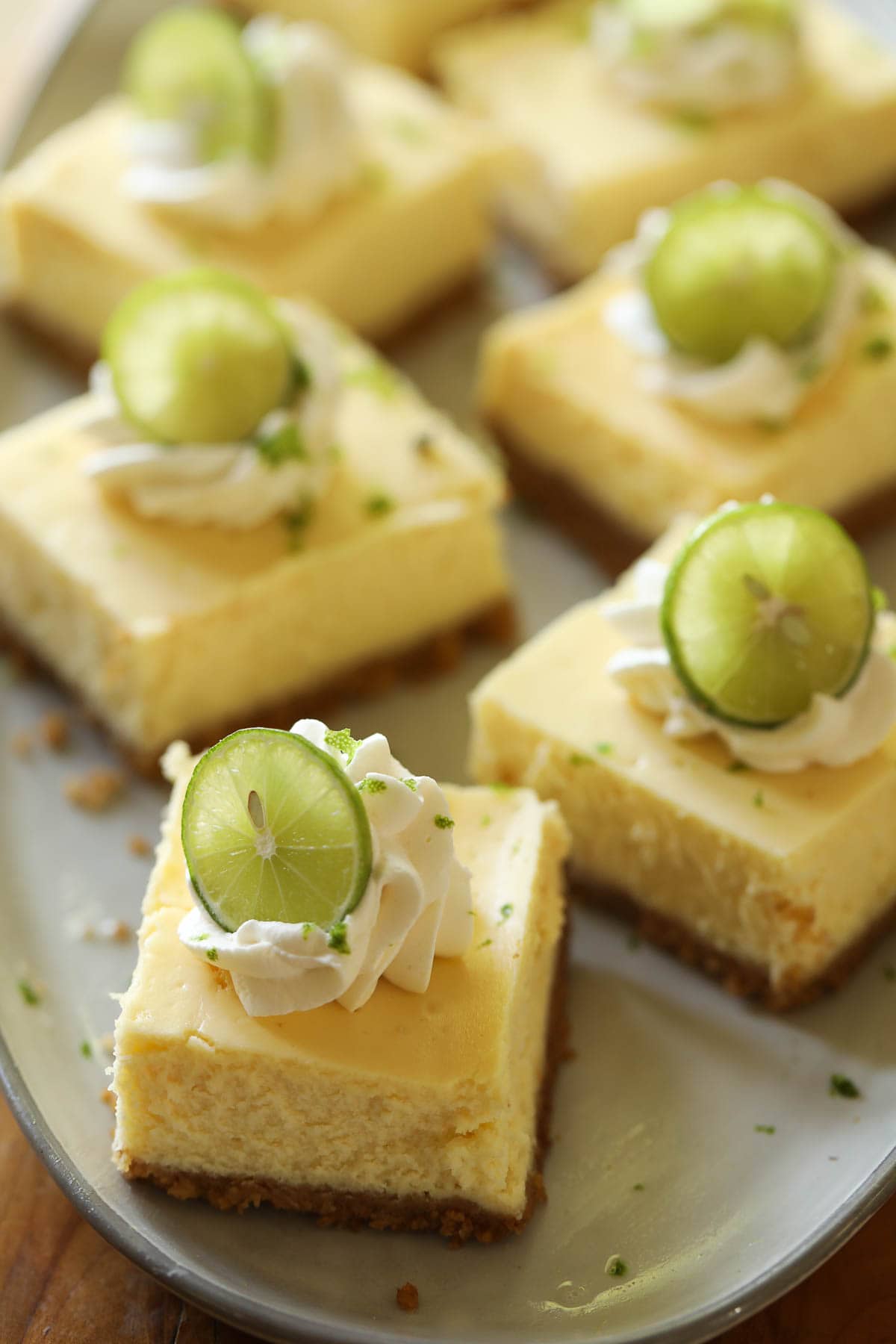 many cheesecake squares sliced with whipped cream topping.