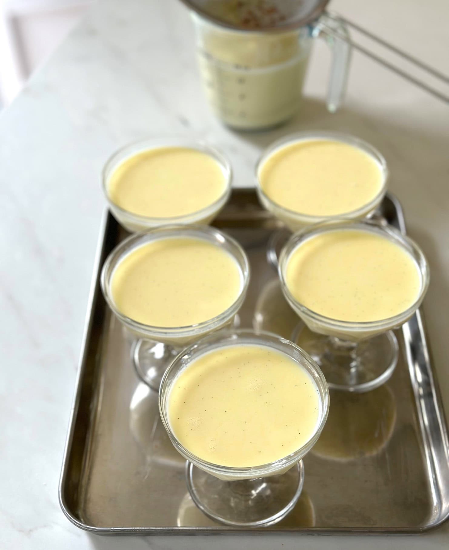 Footed glass dishes filled with strained panna cotta mixture