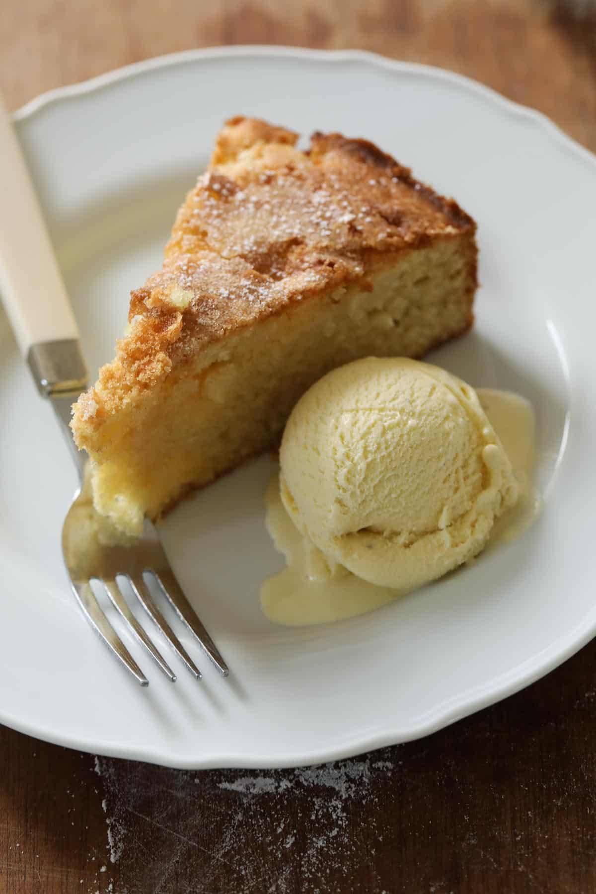 A slice of apple cake on a plate with a scoop of vanilla ice cream