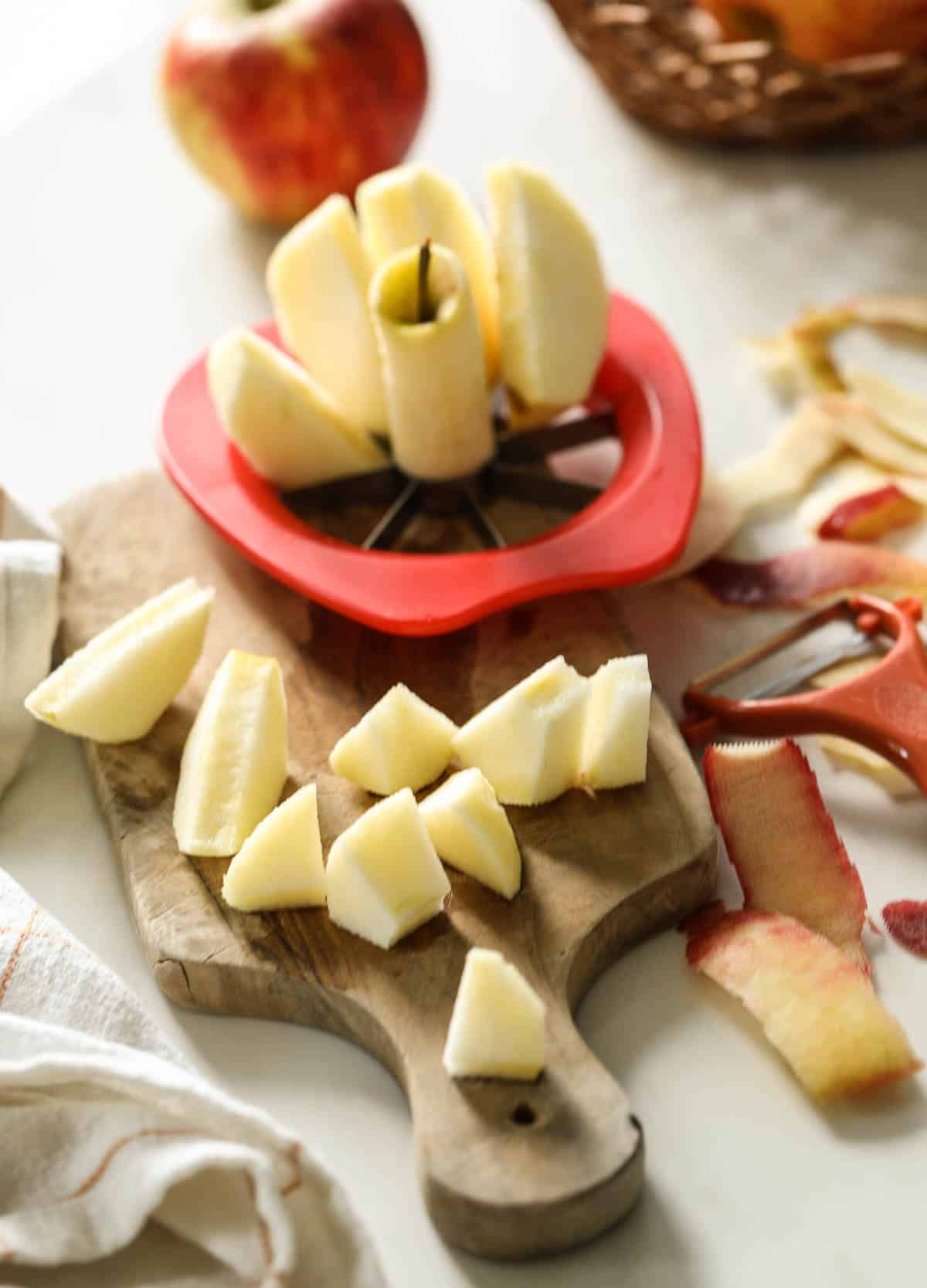 Tart apples being cut with an apple slicer and chopped on a cutting board