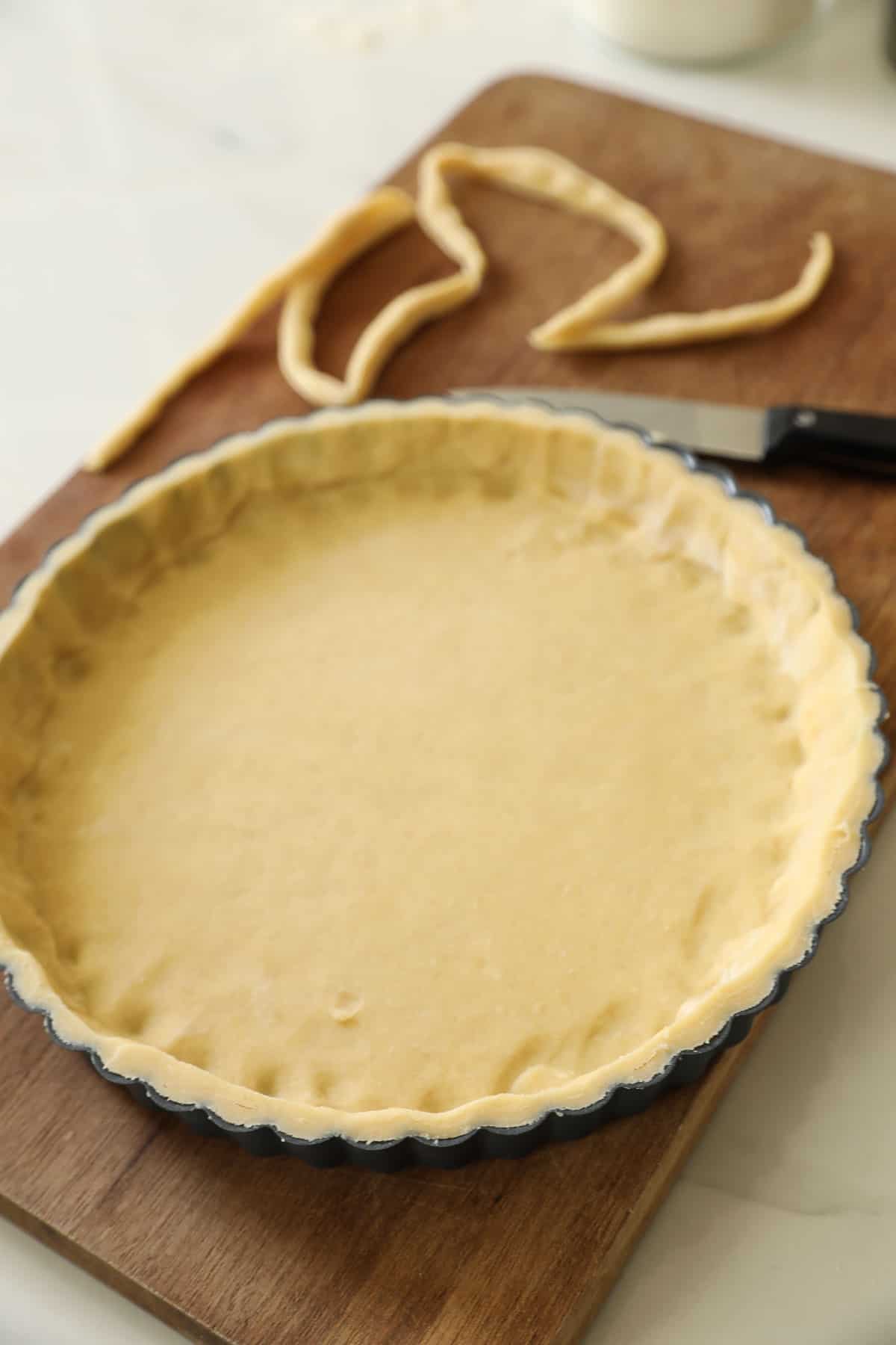 A trimmed tart shell with dough