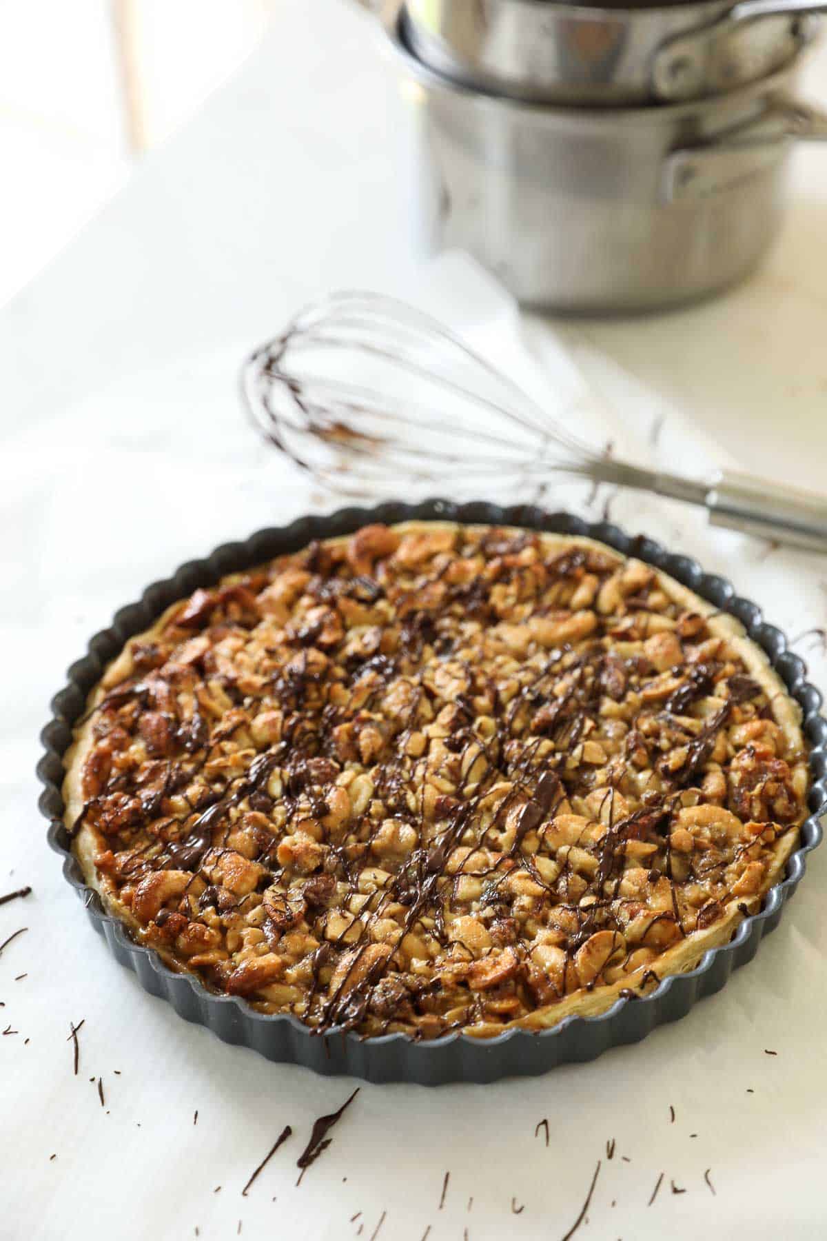 A nut tart drizzled with chocolate.