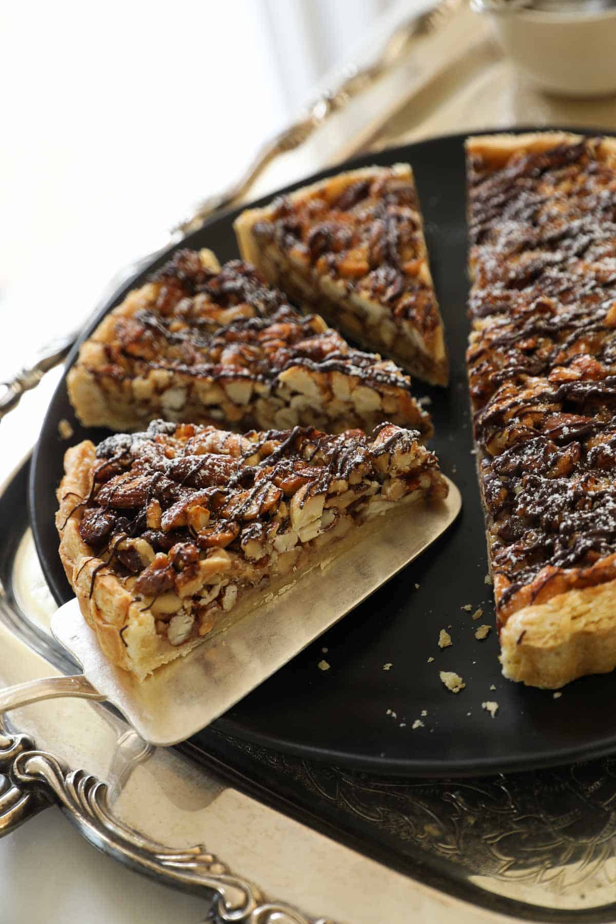 a slice of nut tart on a serving platter with other slices. 