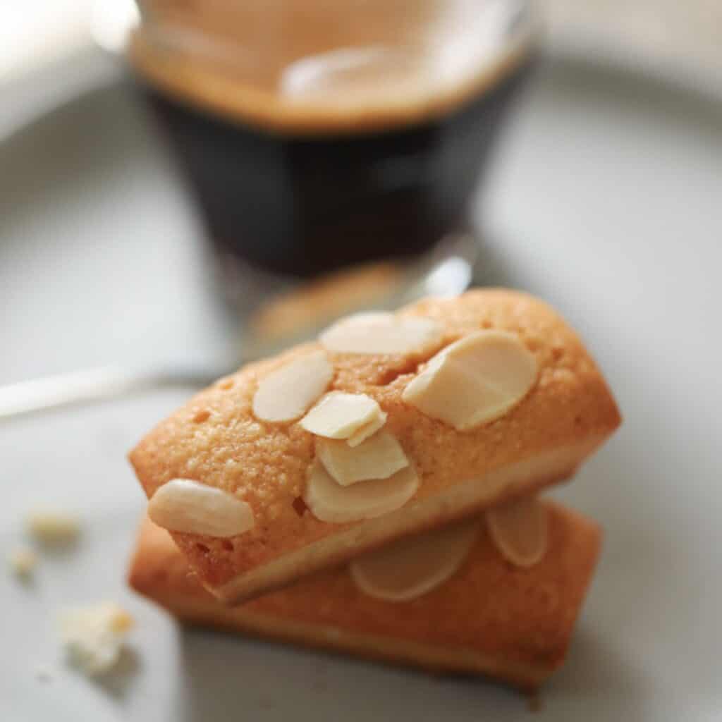 Small cookies with almonds stacked on a plate.