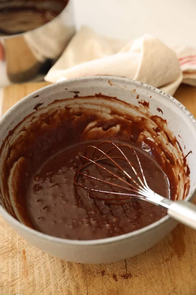 A bowl of chocolate mixed with a whisk.