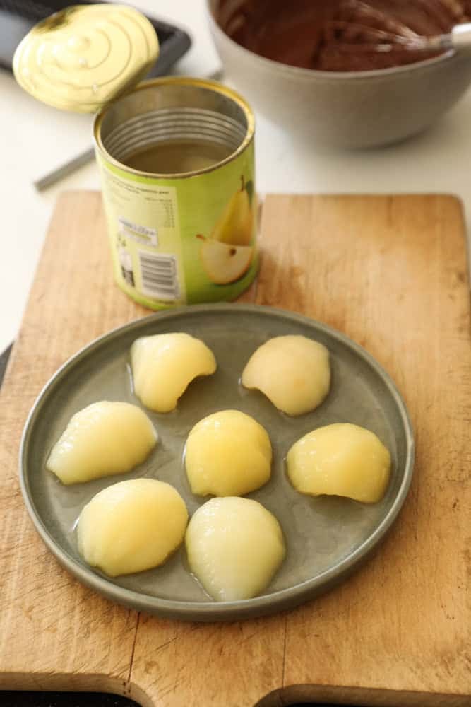 Canned Pears on a plate sitting on a cutting board with a can in the background.