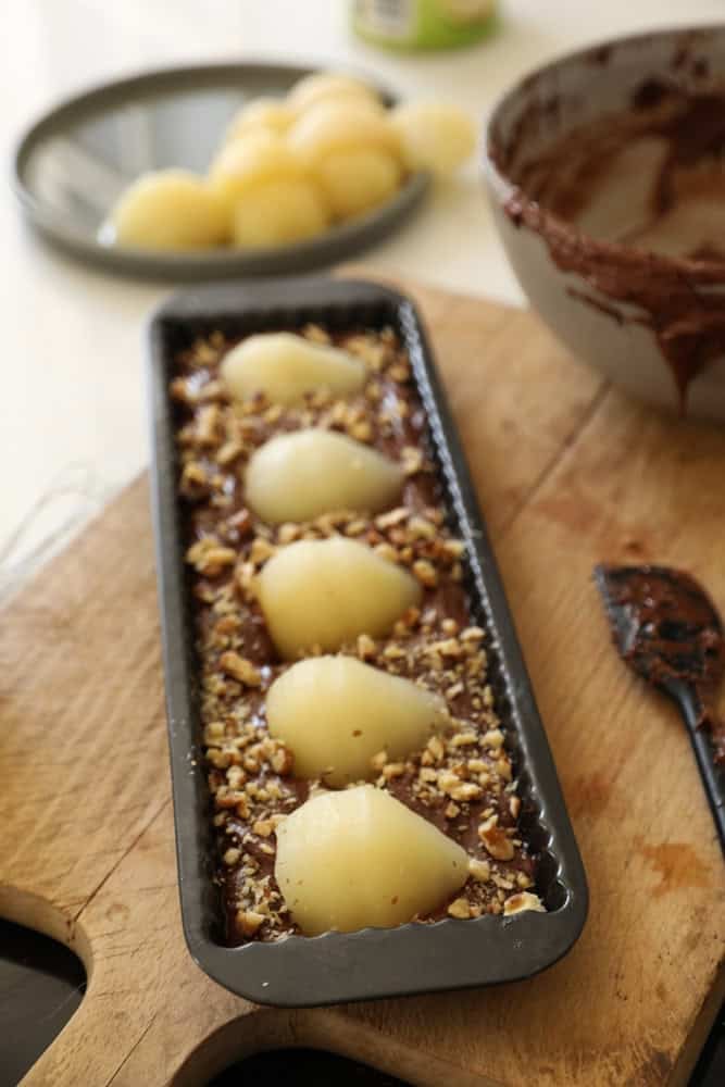 a rectangular tart tin filled with chocolate brownie batter, pears and walnuts.