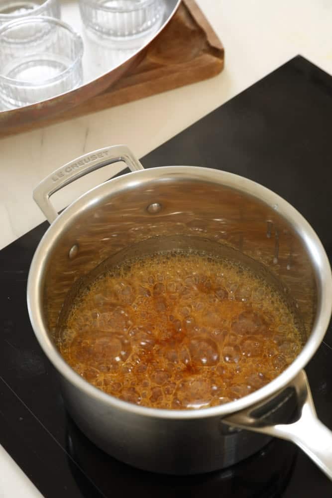 A dark amber caramel forming in a pot.