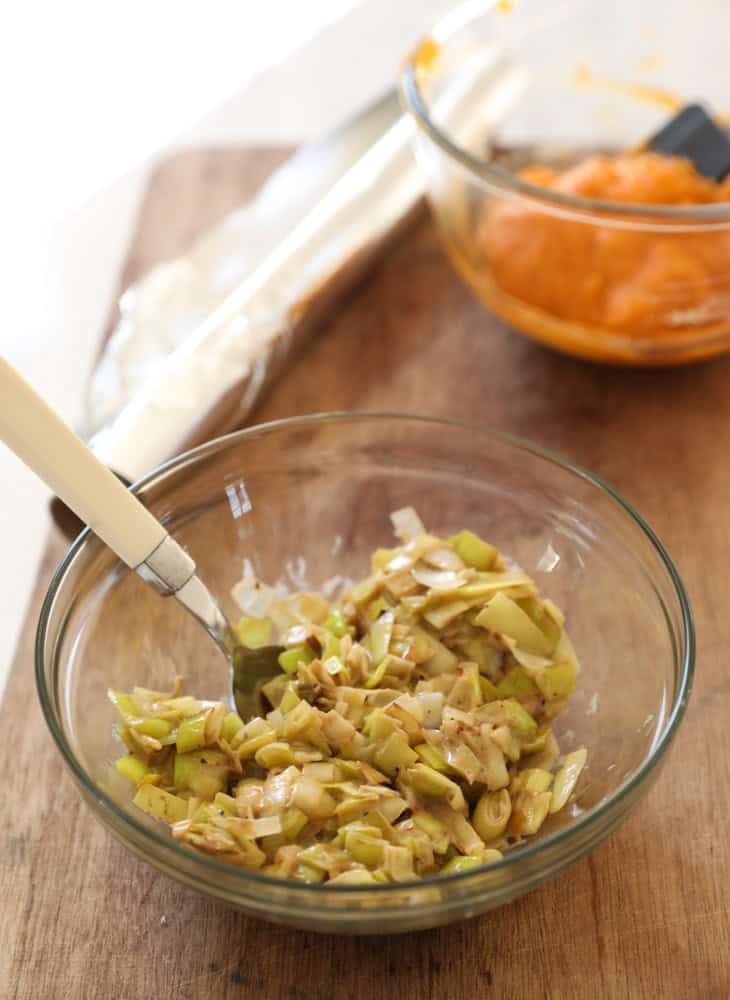 A bowl of creamy leeks and sweet potato puree on a cutting board.