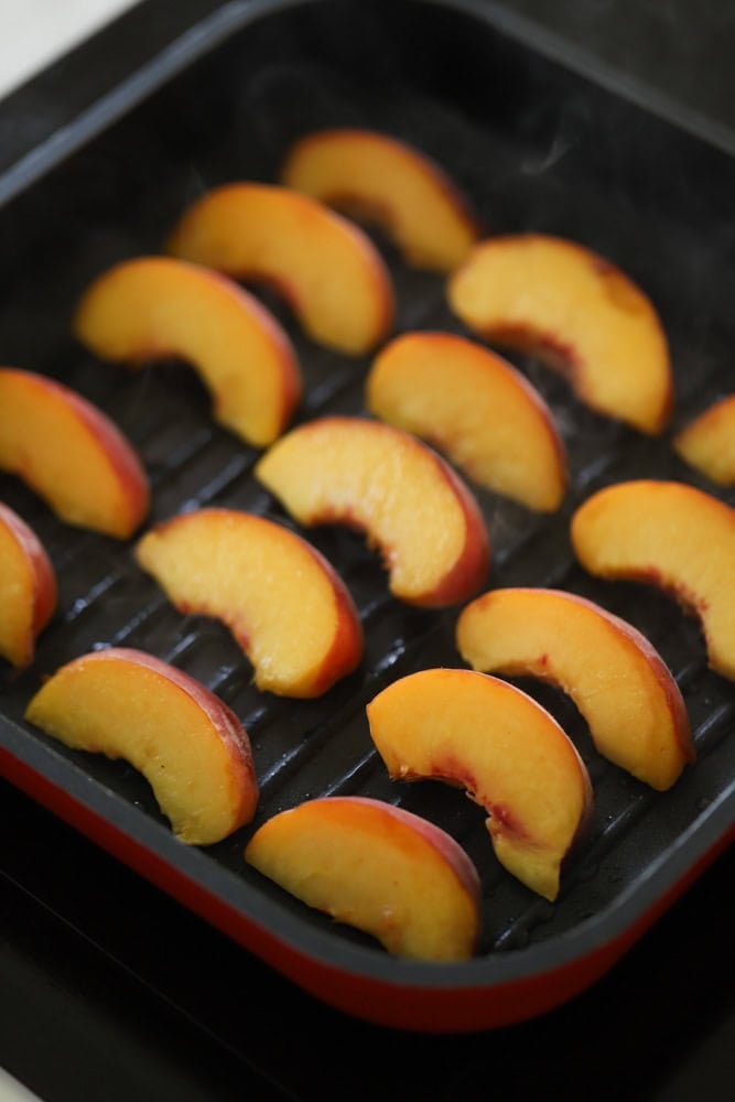 sliced peaches grilling on a grill pan.
