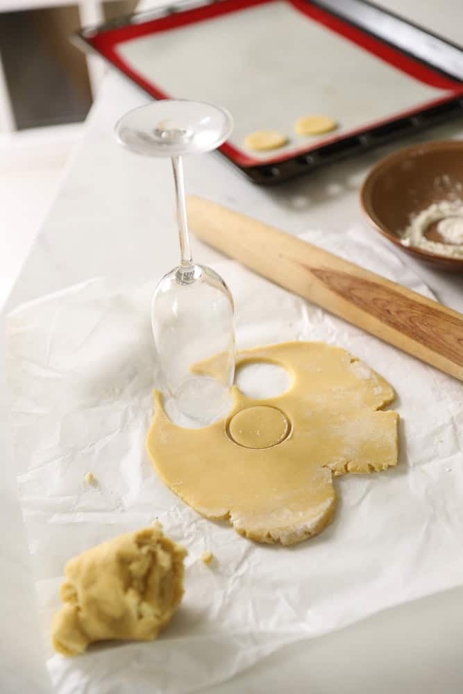 Cookie dough being cut out with a champagne glass.