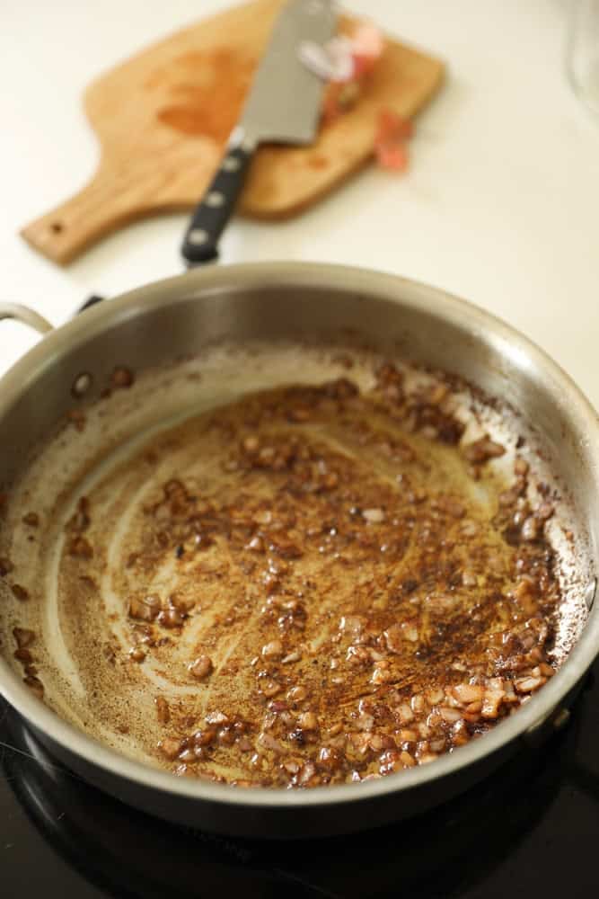 Shallots in a pan cooking in beef fat. 
