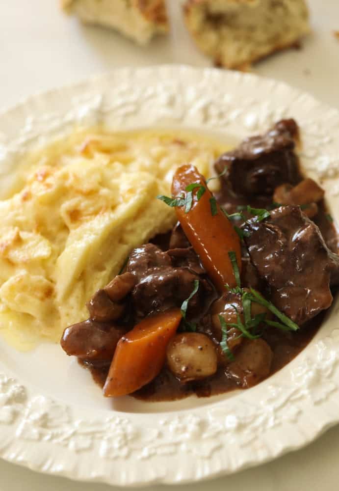 a plate of beef bourguignon and gratin dauphinois on the side.