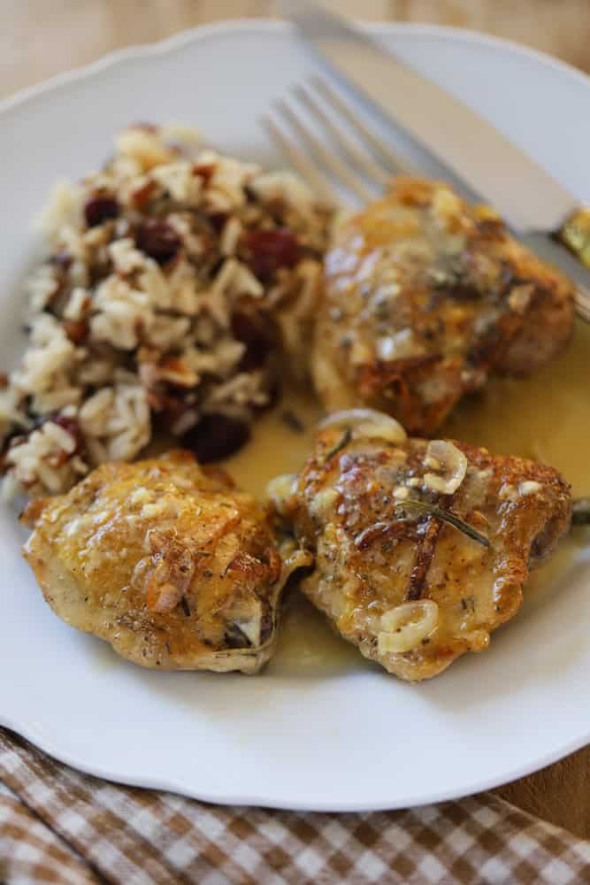 crispy chicken breasts with sauce on a plate with wild rice, cranberries and pecans.