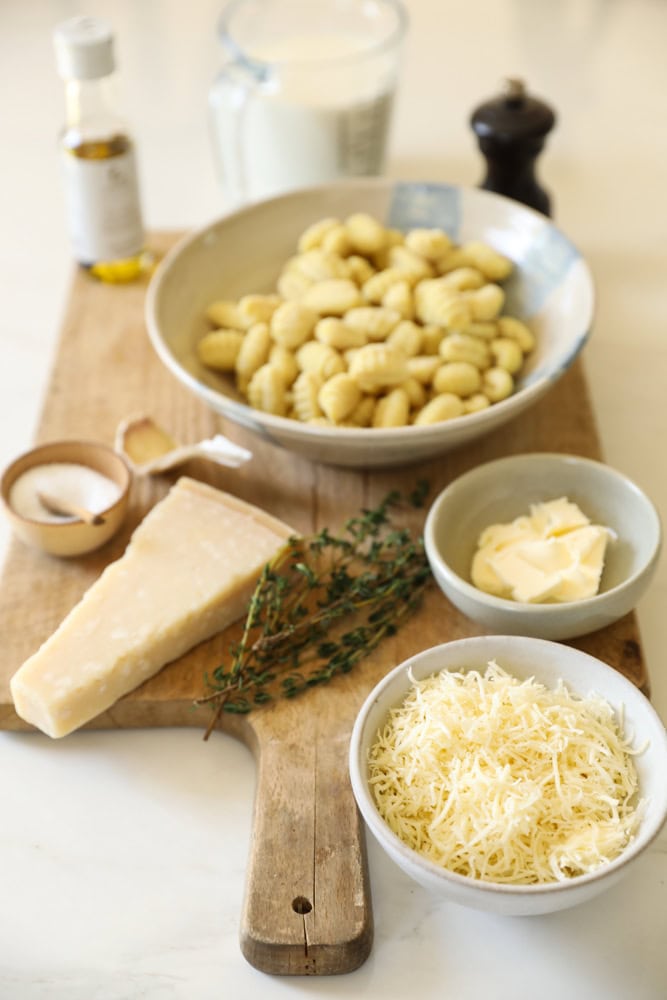 shelf stable gnocchi, parmesan cheese, fresh thyme, seasonings and milk on a counter.