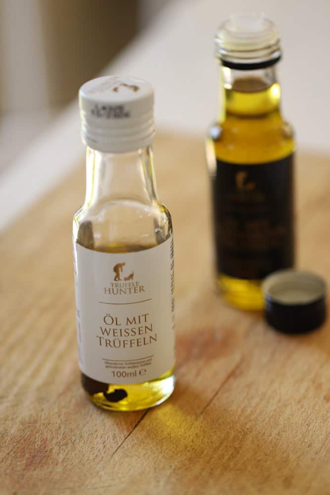 two bottles on truffle oil on a counter, white truffle oil and black truffle oil.