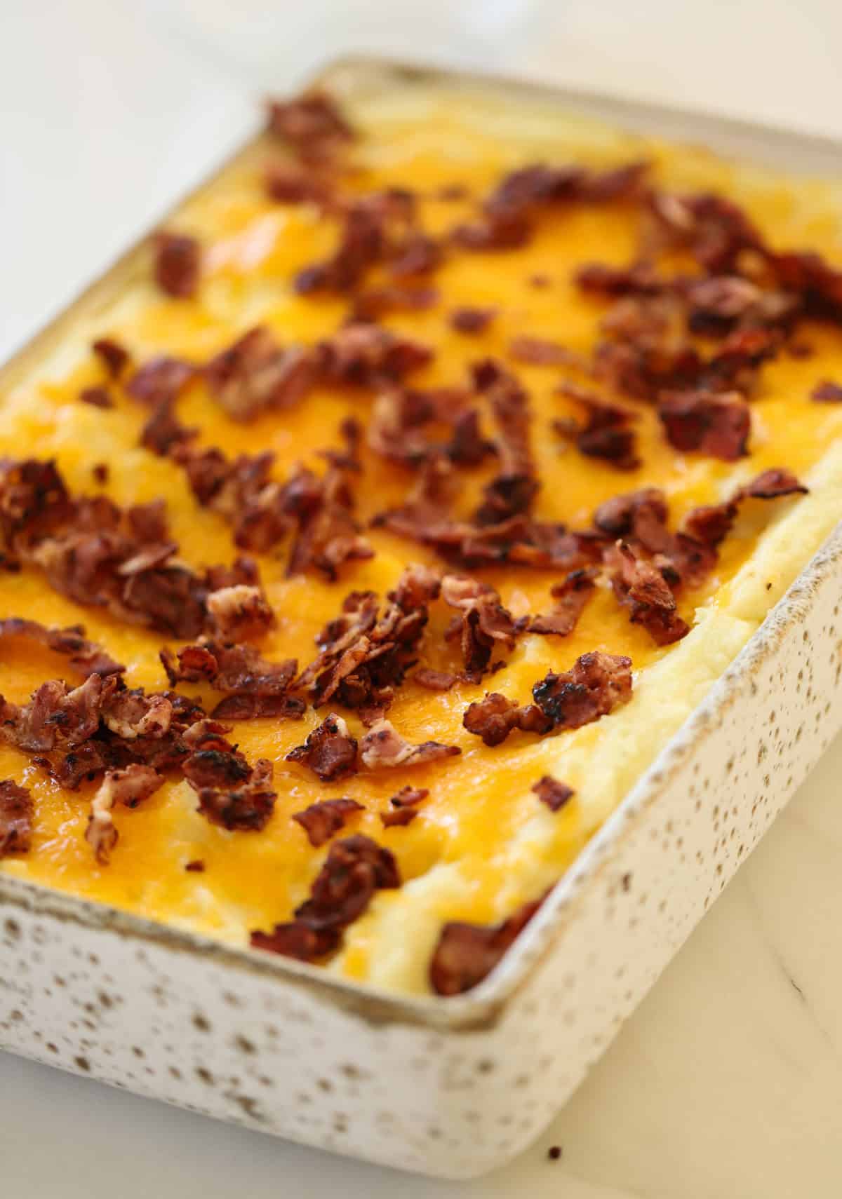 a potato casserole topped with melted cheese and bacon.