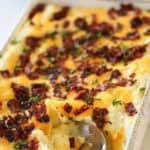 Twice Baked Potato Casserole with a serving spoon taking a scoop of of it.