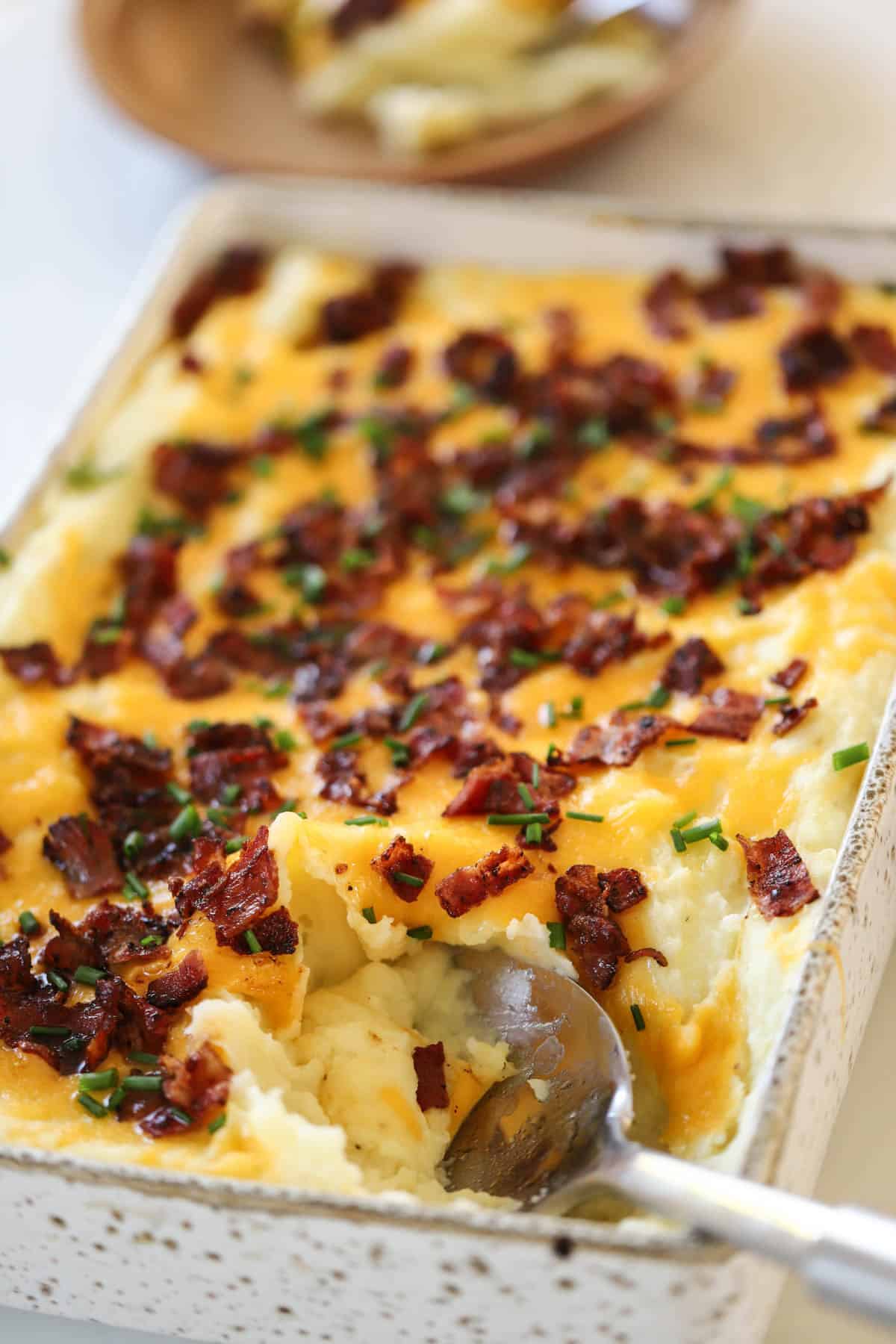 Twice Baked Potato Casserole with a serving spoon taking a scoop of of it.