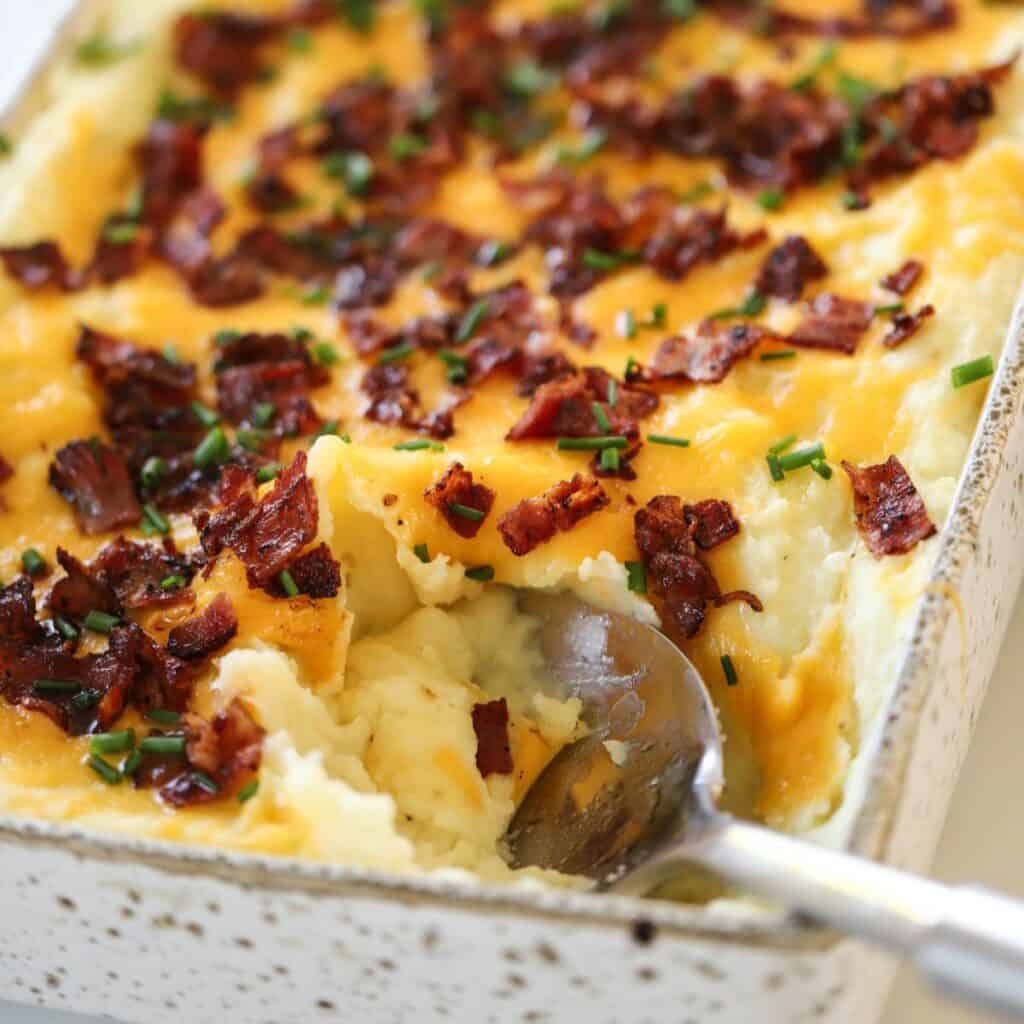 A spoon taking a scoop out of a potato casserole.