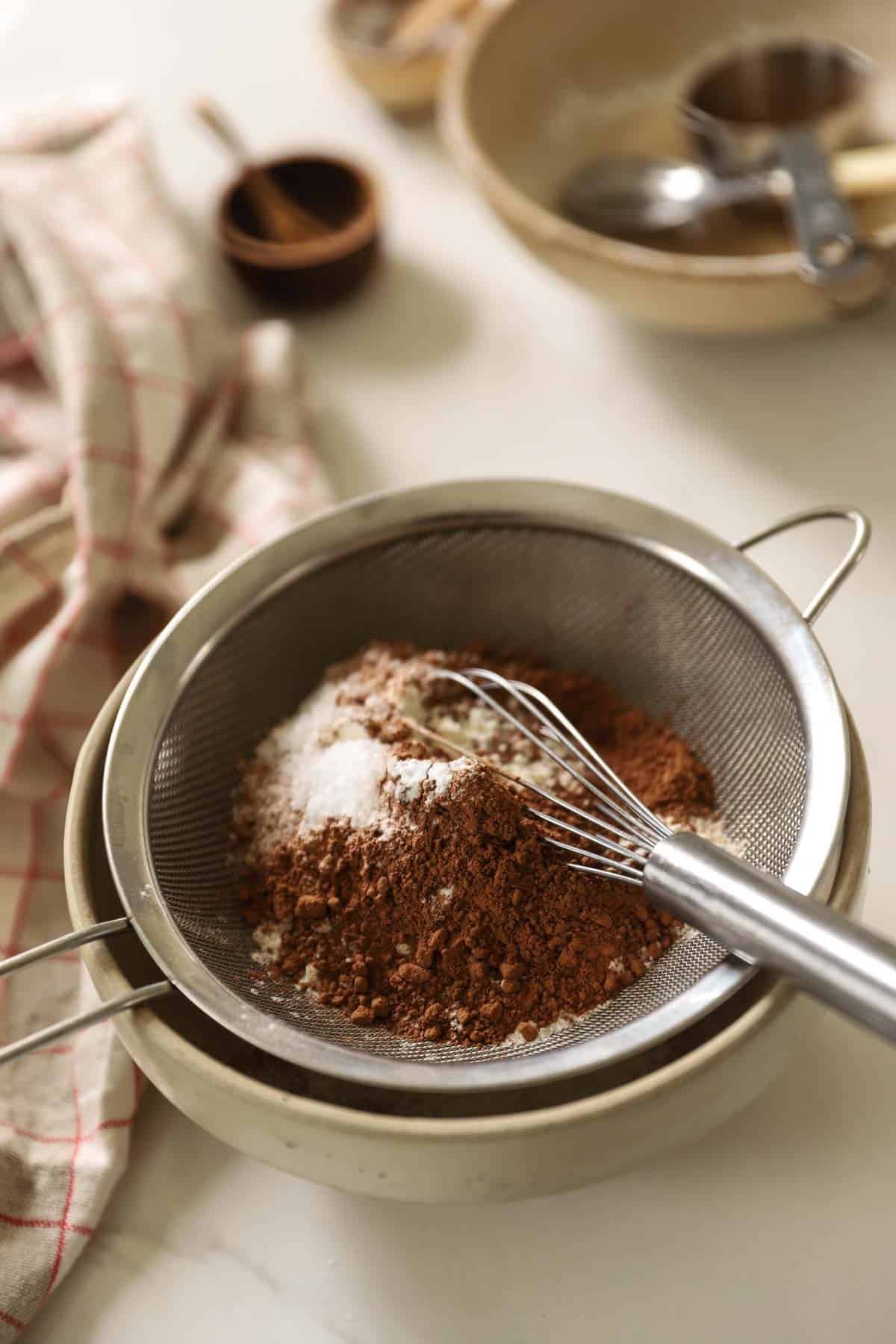 Sifting flour, cocoa powder and other dry ingredients in a sieve.