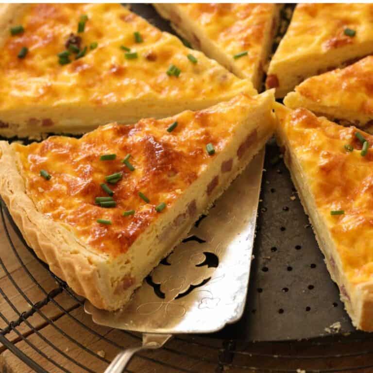 A sliced piece of quiche with bacon and a silver pie server