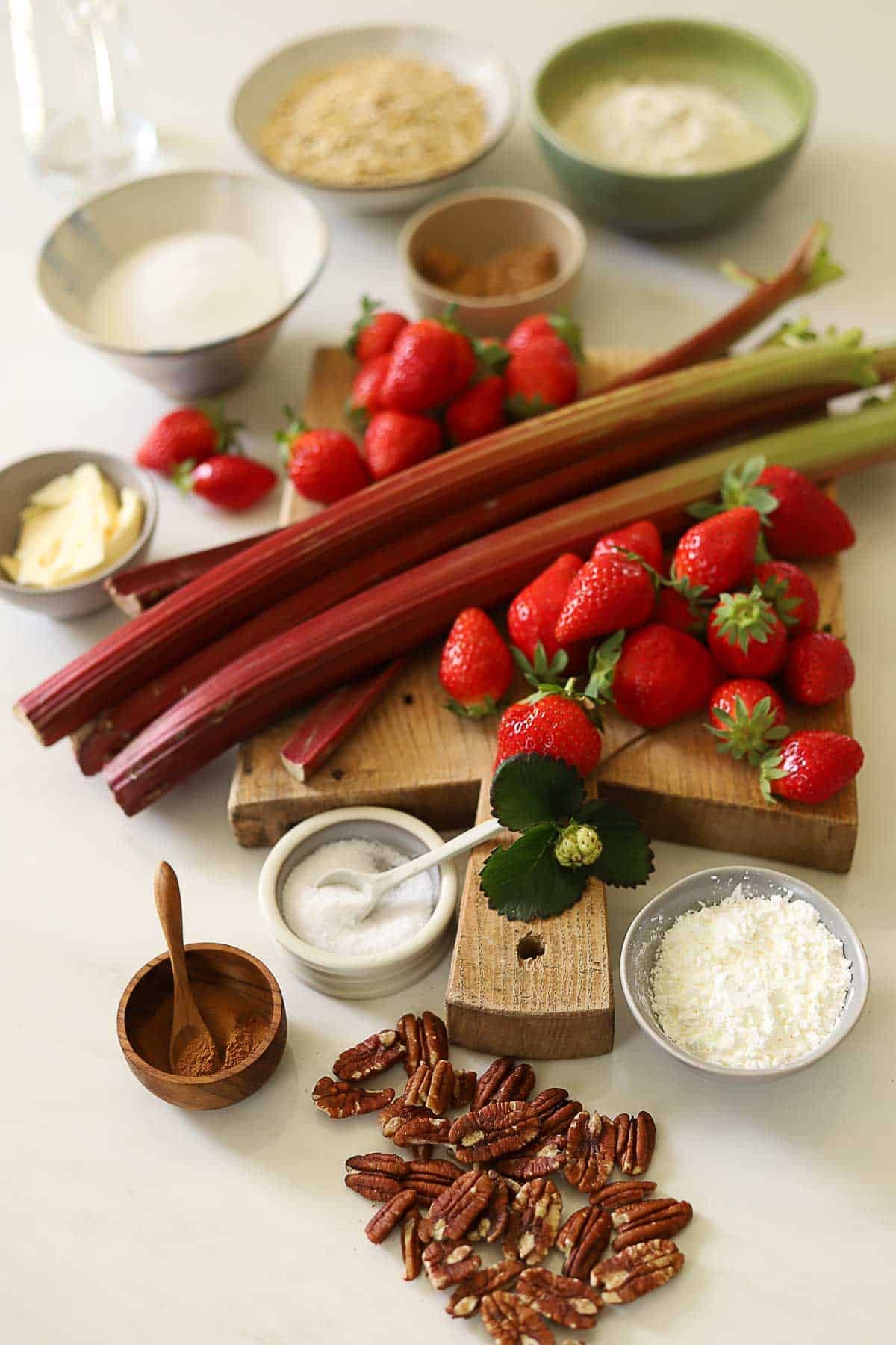 Rhubarb stalks and strawberries and other ingredients laid out to make a fruit crisp.