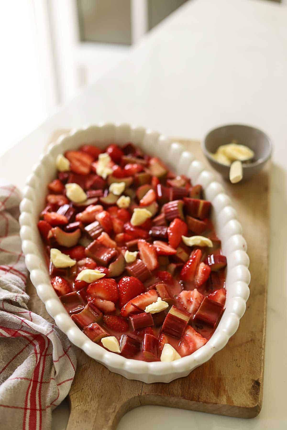 A fruit filling dotted with butter in an oval baking dish.
